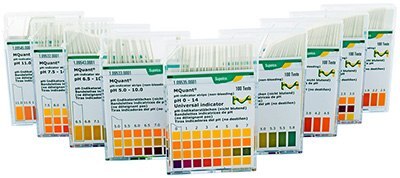 A series of plastic containers with pH indicator strips, arranged in a row. Each container has a label displaying different pH ranges and corresponding color charts for pH testing, with some featuring graphs or additional scientific data. The packaging is primarily green and orange with white text, and each box is designed to dispense the strips for easy access.