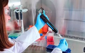 The image depicts a person in a lab coat conducting an experiment using a lab equipment.