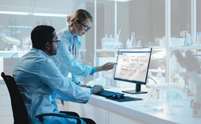 Data Visualization and Analytics Software for Biotech Two scientists in the lab reviewing bioprocessing data visualizations on a computer monitor