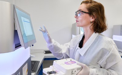 BioReliance® Next Generation Sequencing Female lab technician with lab protection cloth working on a computer.