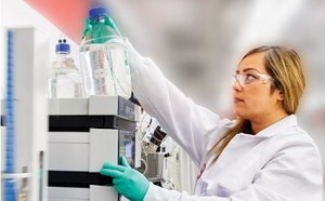 Purification of DNA and RNA oligos Lab worker looking at a bottle of fluid on a shelf.